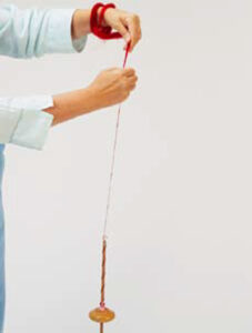 person drafting fibers with a drop spindle